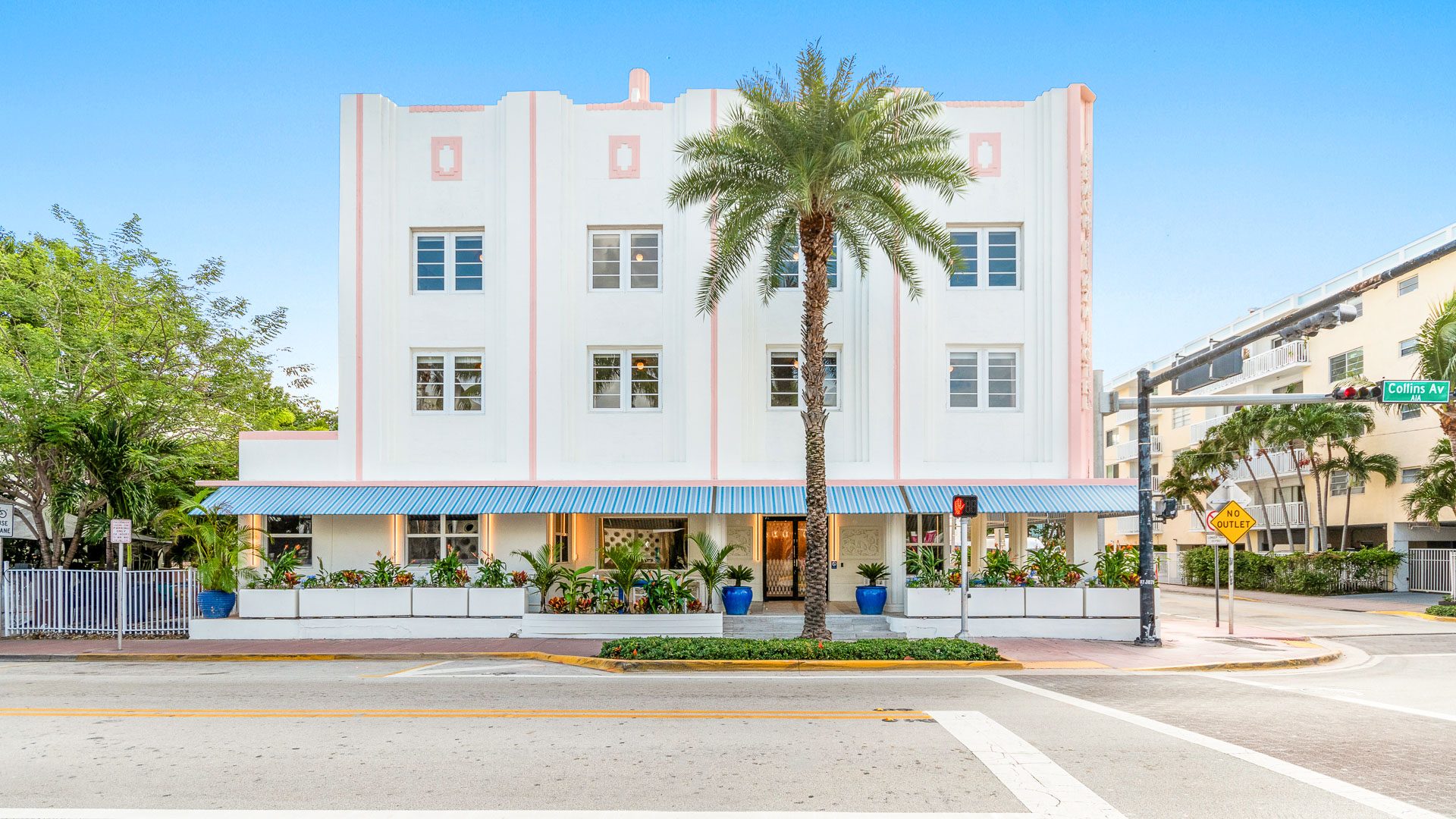 The Corendon Beach Plaza facade at 1401 Collins Avenue: a white three-storey Art Deco building with pink trim and palm trees